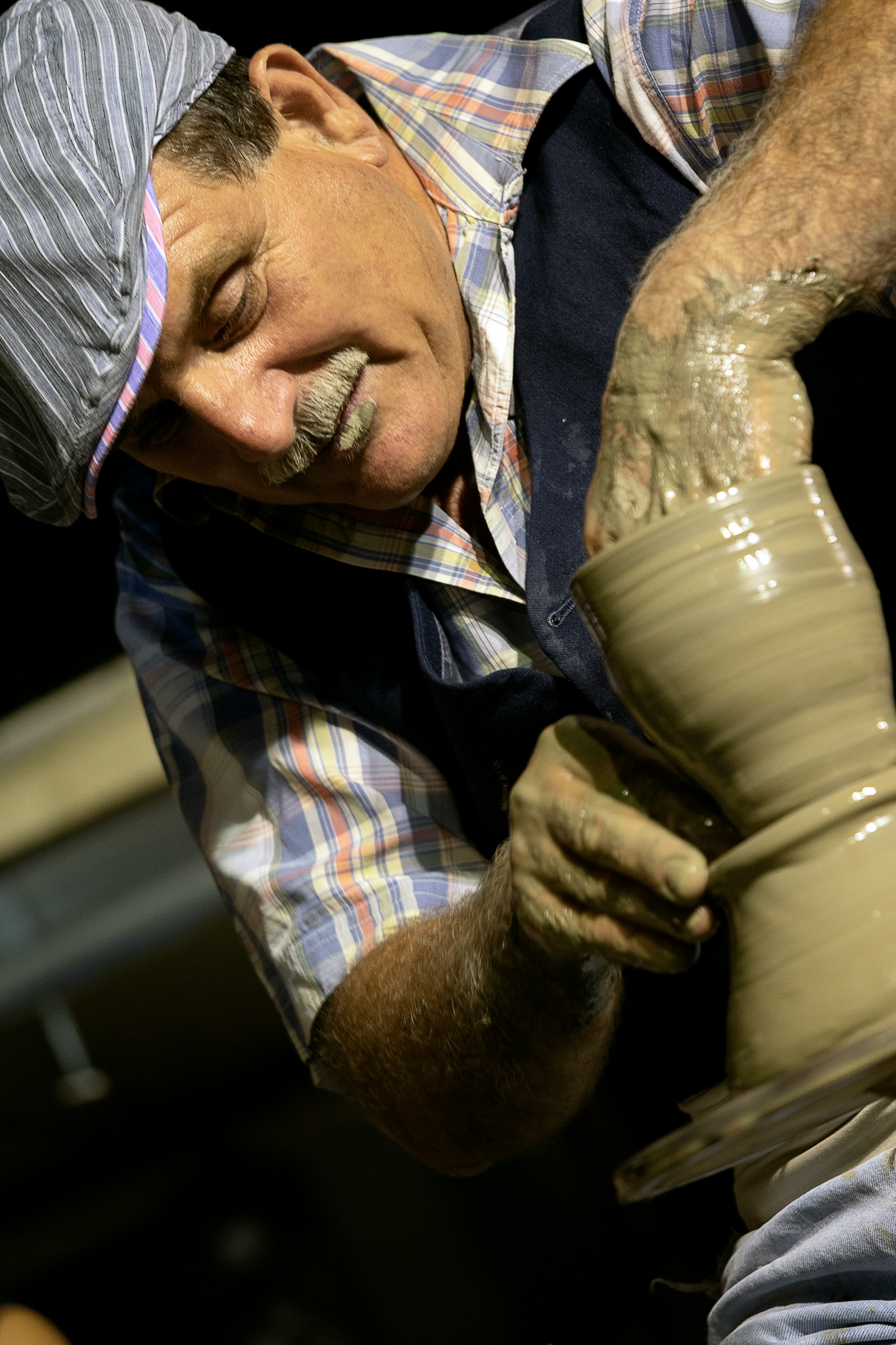 man in blue white and red plaid button up shirt holding brown clay pot